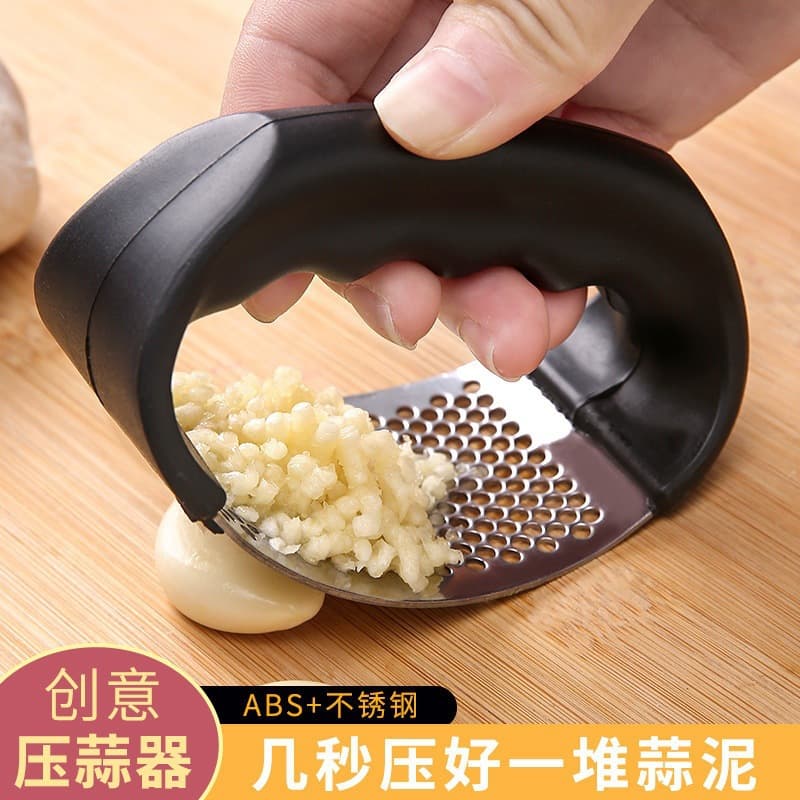 Small portable stainless steel manual garlic press, garlic mincer, and home crushing tool.