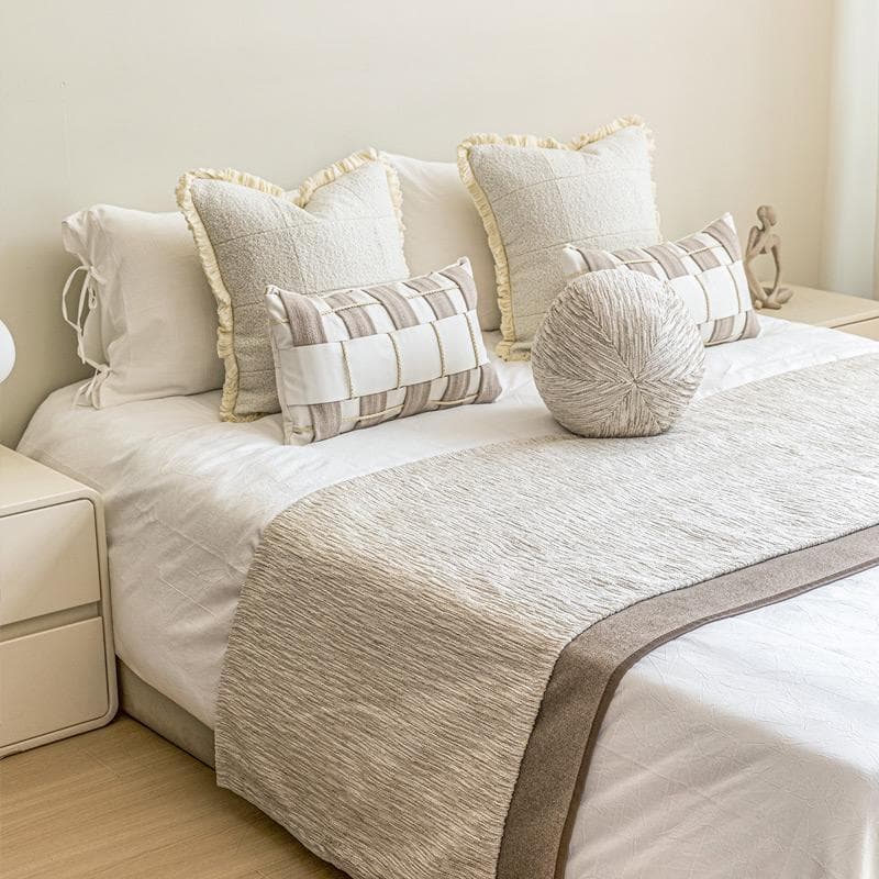 Hotel showroom featuring modern wabi-sabi style beige bedding, pillows, blankets, and high-end soft furnishings in multi-piece sets.