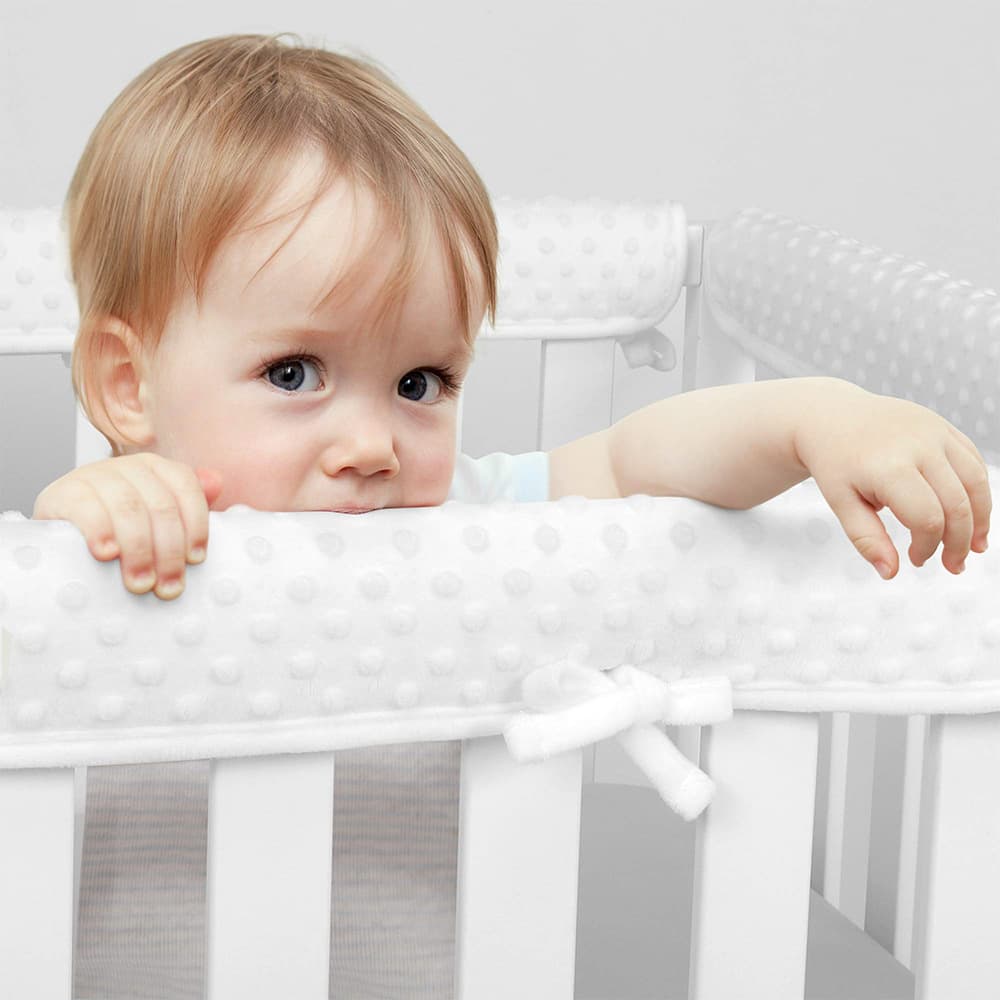 Baby crib railing with plush edging to prevent chewing and collisions.
