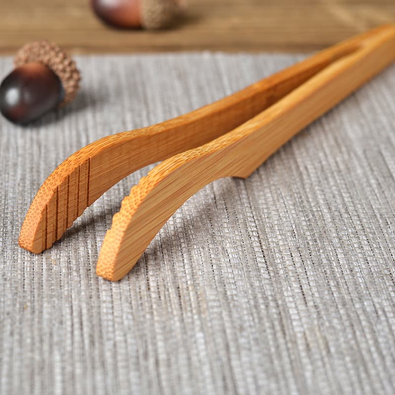 Wholesale bamboo tongs for domestic use, featuring serrated edges for secure grip on cups, customizable with logos for tea ceremony needs.