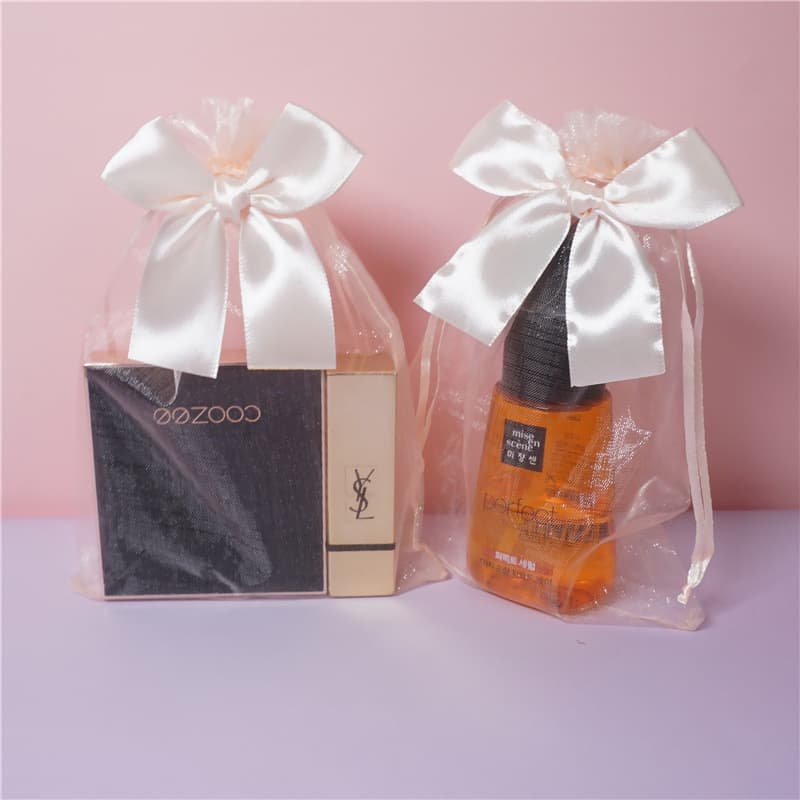 Champagne-colored transparent gift bag with bow drawstring closure, suitable for skincare product samples.