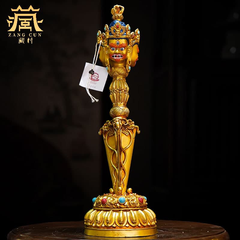 Fully gilt three-sided Puba vajra with painted face and gemstone inlaid vajra prong with base copper ornament