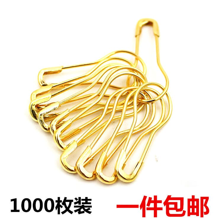 Small gold-colored clothing store label pins, brooches for securing garments, large safety pins, and curved clips.