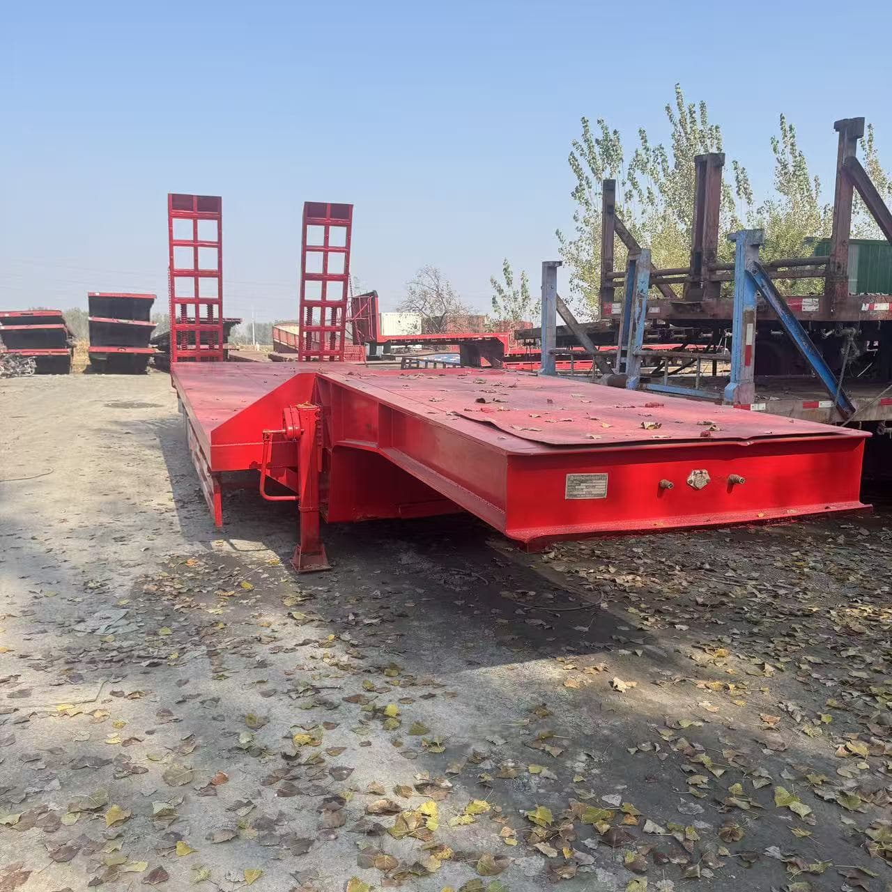 13.75-meter pull-out low flatbed semi-trailer with ladder for excavators, 3 axles, for transporting heavy loads.
