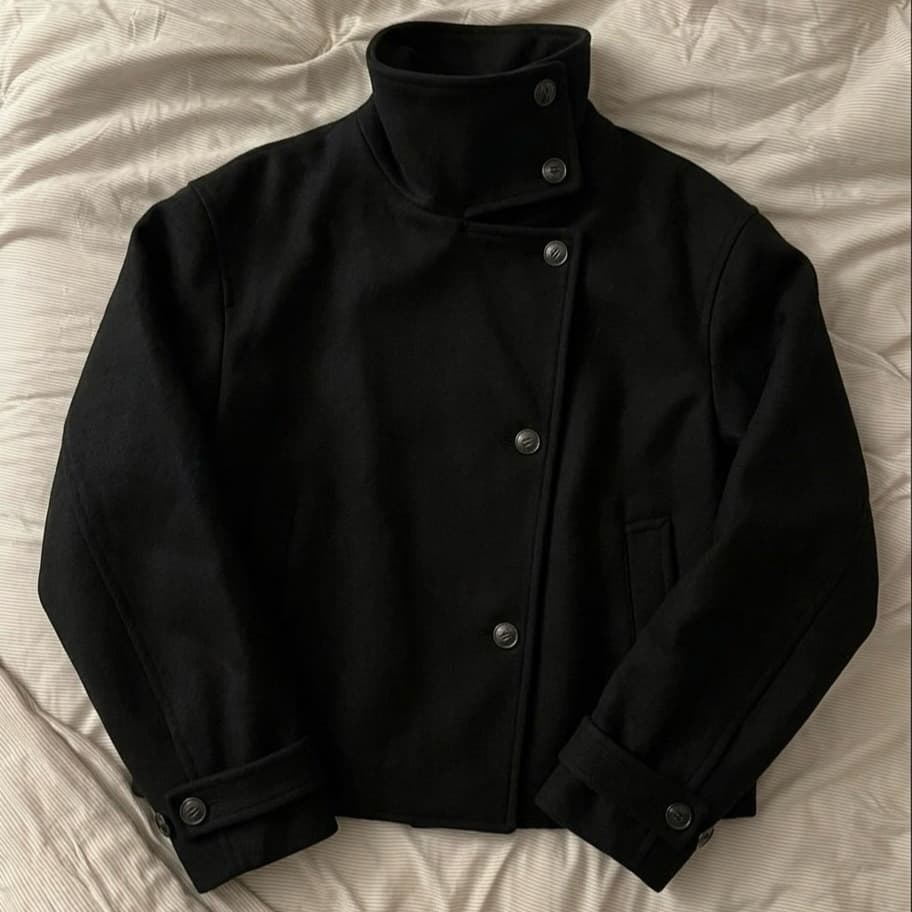 Minimalist High-End Black Cropped Wool Jacket with High Stand Collar, Asymmetric Button Closure, Folded Cuffs, Structured Silhouette Coat